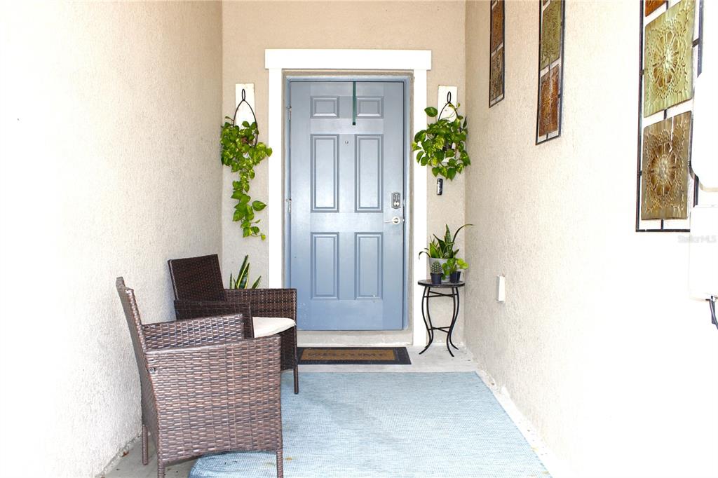 A covered entryway features a blue front door, two wicker chairs, and potted plants — 30798 VERIDIAN WAY, WESLEY CHAPEL, FL
