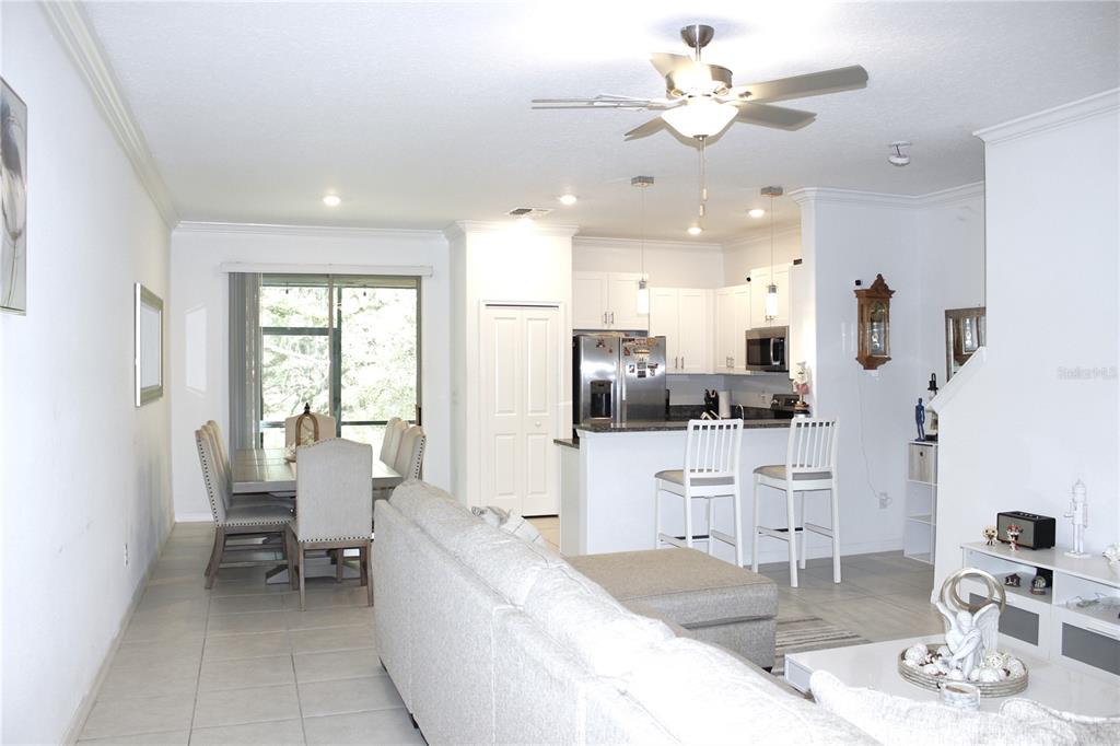 An open-concept living and dining area features tile flooring, a kitchen island, and white cabinetry — 30798 VERIDIAN WAY, WESLEY CHAPEL, FL