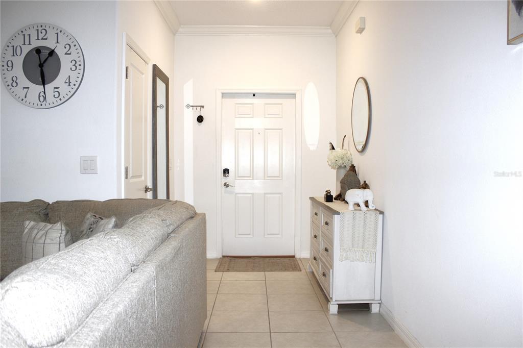 An entryway features a white door, a light-colored dresser, a wall clock, and tile flooring — 30798 VERIDIAN WAY, WESLEY CHAPEL, FL