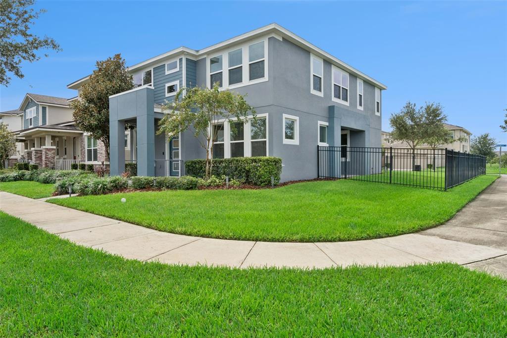 A two-story gray house with a fenced side yard and a sidewalk in the foreground — 16602 WINGSPREAD LOOP, WINTER GARDEN, FL