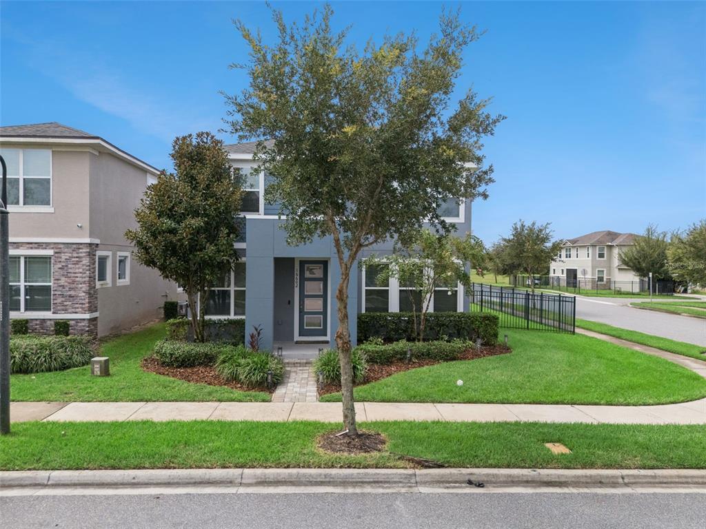 A two-story gray house with a front yard, a tree, and a paved walkway — 16602 WINGSPREAD LOOP, WINTER GARDEN, FL