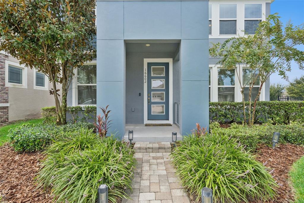 A blue two-story house exterior features a front door with four glass panels and landscaping — 16602 WINGSPREAD LOOP, WINTER GARDEN, FL