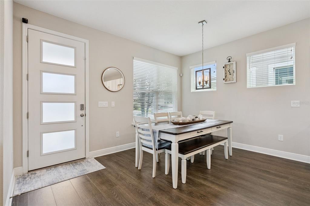 A dining area features a white table with a bench, chairs, and a front door — 16602 WINGSPREAD LOOP, WINTER GARDEN, FL