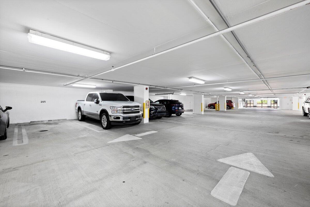 An indoor parking garage with concrete floors, white pillars, and several parked vehicles — 3590 Coral Way # 502, Miami FL 33145, MIAMI, FL