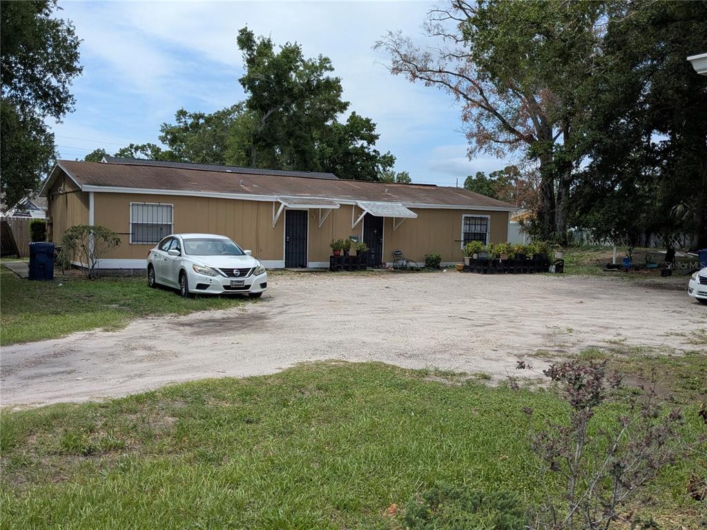 A single-story tan house with a gravel driveway and two front entrances — 3016 N 48TH STREET, TAMPA, FL