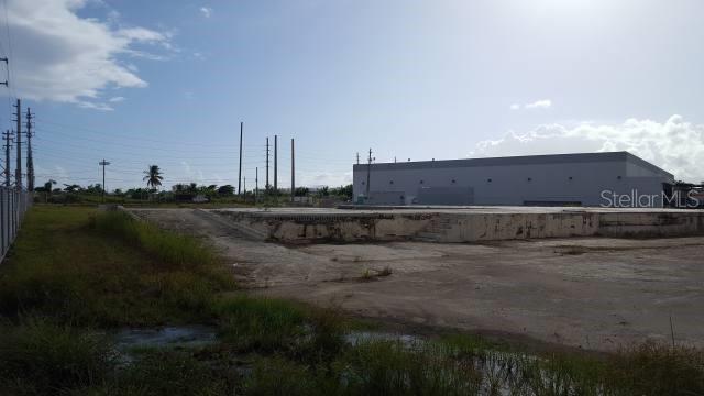 A large concrete foundation slab sits in an open lot next to a warehouse building — 3 PR-3 KM 77.9, HUMACAO, PR