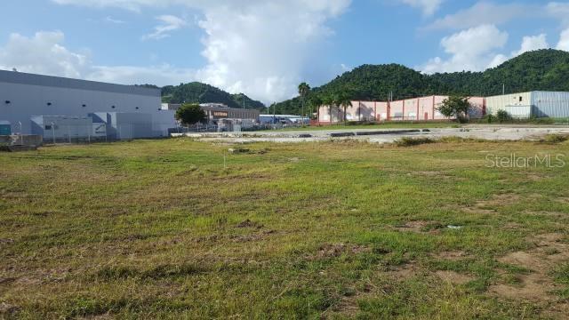 A large, flat, grassy vacant lot sits in front of industrial buildings and green hills — 3 PR-3 KM 77.9, HUMACAO, PR