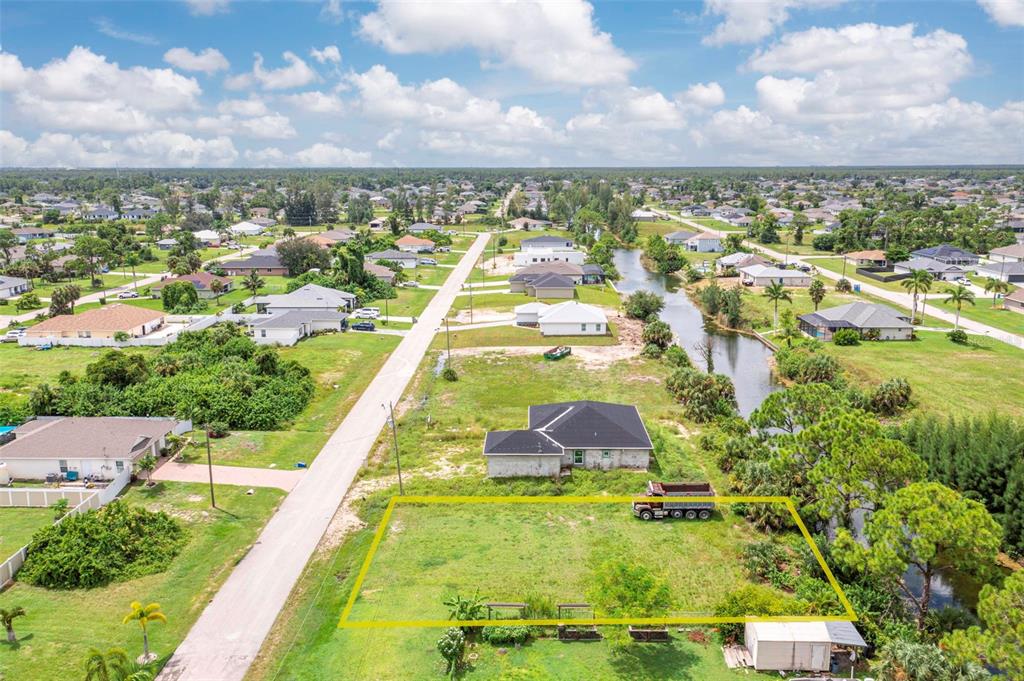 An aerial view shows a vacant rectangular lot next to a house and a canal — 1623 NE 36TH LANE, CAPE CORAL, FL