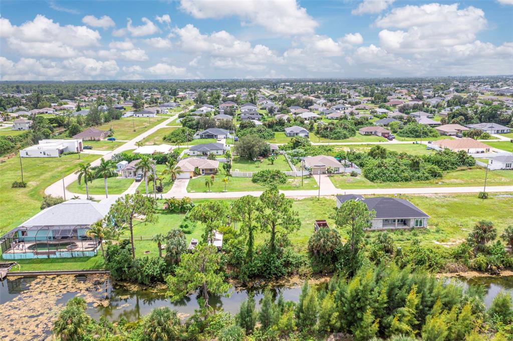 An aerial view shows a suburban neighborhood with houses, green lawns, and a canal — 1623 NE 36TH LANE, CAPE CORAL, FL