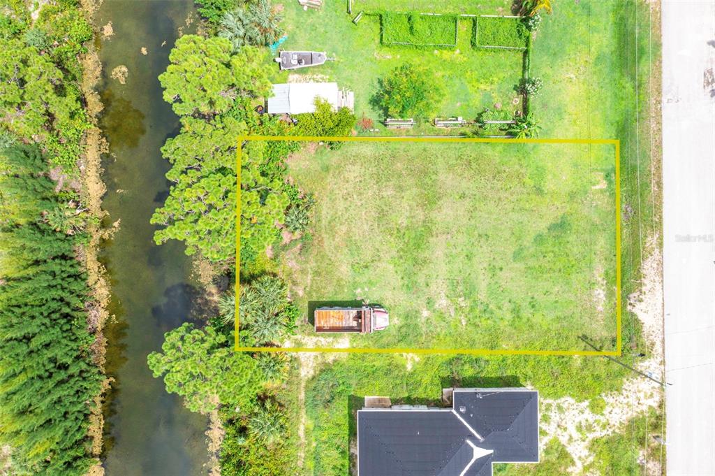 An aerial view shows a rectangular vacant lot bordered by a canal and a road — 1623 NE 36TH LANE, CAPE CORAL, FL