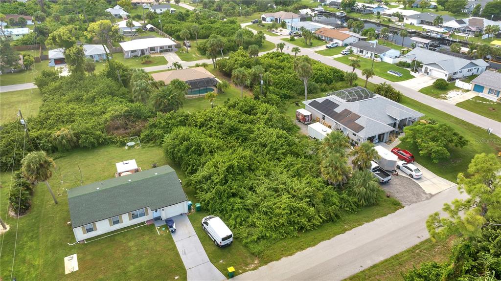 An aerial view shows two houses separated by a large, densely wooded vacant lot — 4469 BRINTNALL STREET, PORT CHARLOTTE, FL