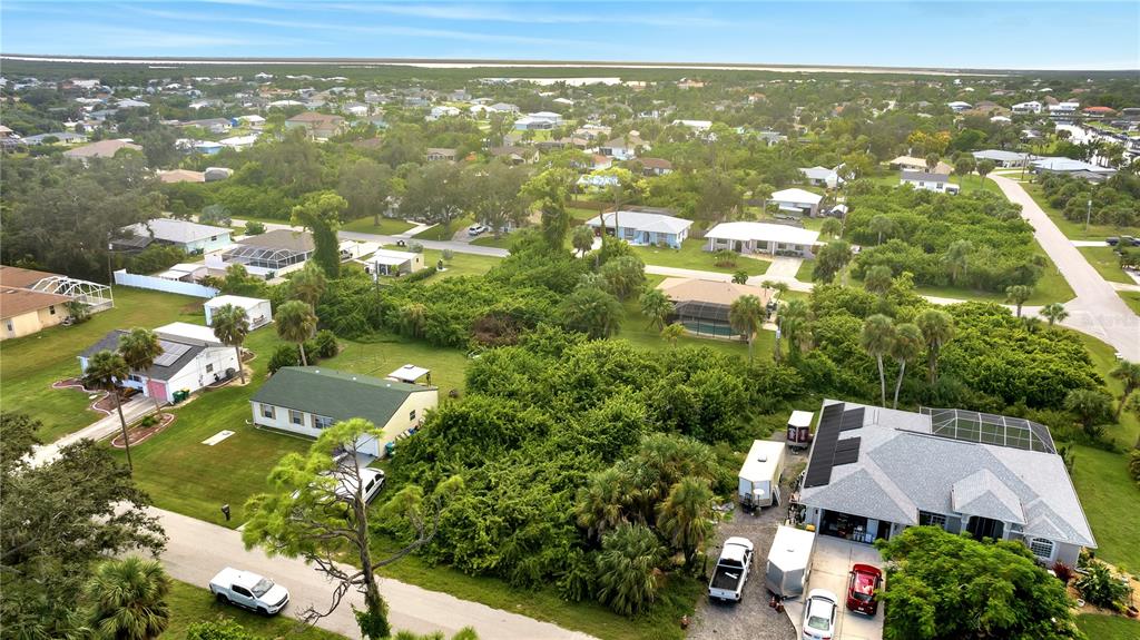 An aerial view shows several houses with pools and driveways surrounded by dense green vegetation — 4469 BRINTNALL STREET, PORT CHARLOTTE, FL