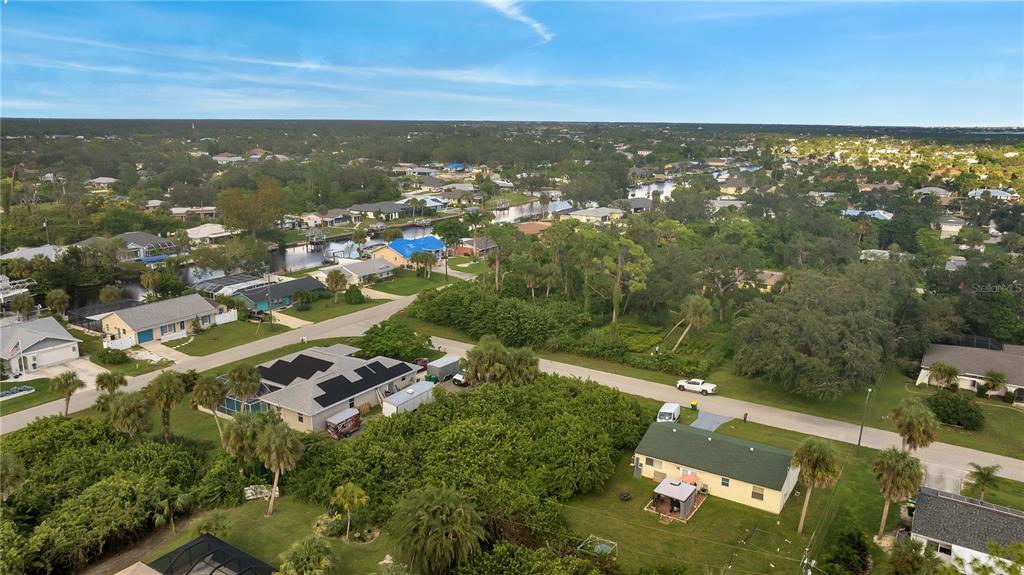 An aerial view shows a residential neighborhood with houses, lush trees, and a canal — 4469 BRINTNALL STREET, PORT CHARLOTTE, FL