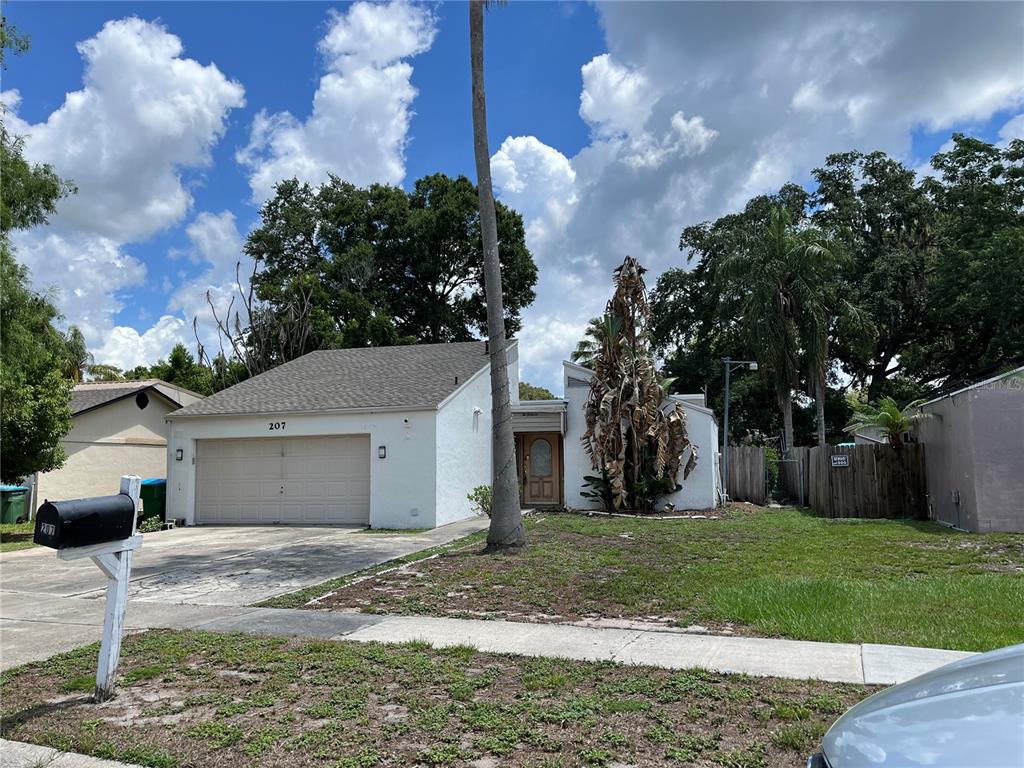 A single-story white house with a two-car garage and a large palm tree in front — 207 BIRCH TERRACE, WINTER SPRINGS, FL
