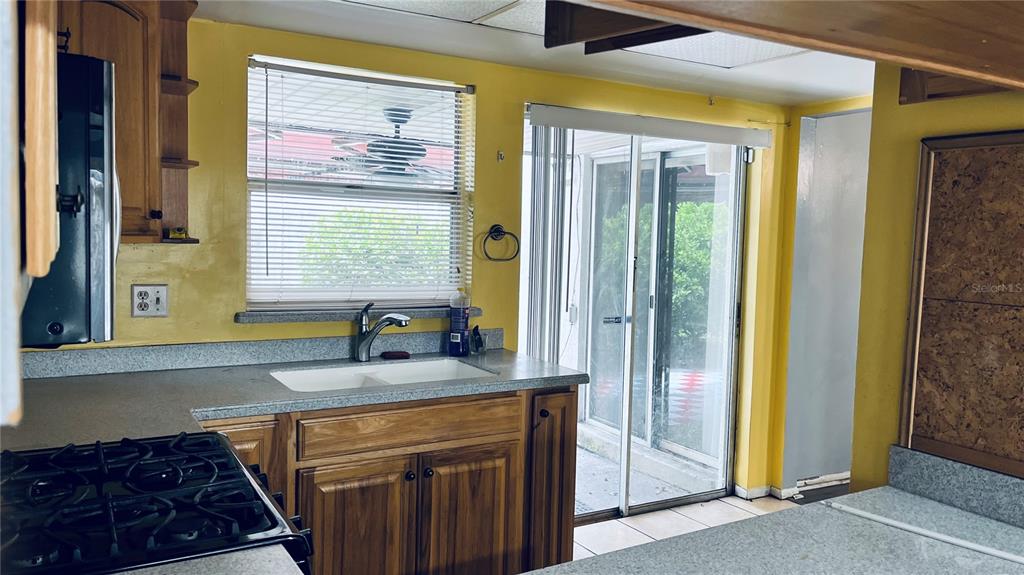 A kitchen features yellow walls, wooden cabinets, a double sink, and sliding glass patio doors — 207 BIRCH TERRACE, WINTER SPRINGS, FL