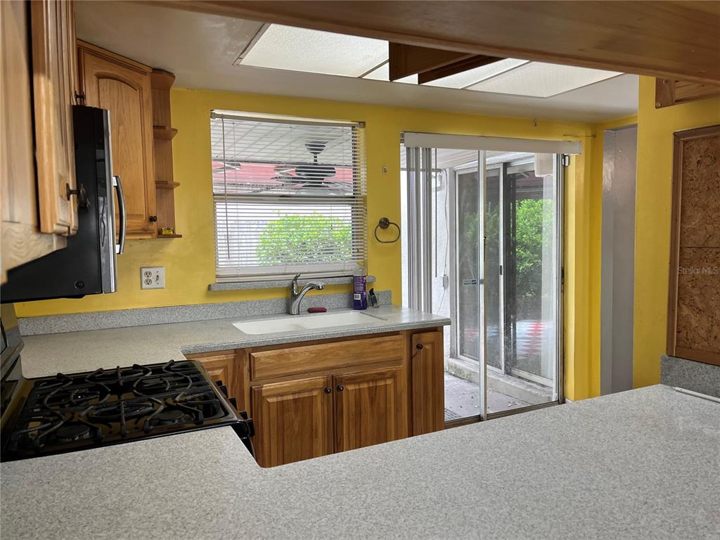 A kitchen with yellow walls, wood cabinets, a gas stove, and a sliding glass door — 207 BIRCH TERRACE, WINTER SPRINGS, FL