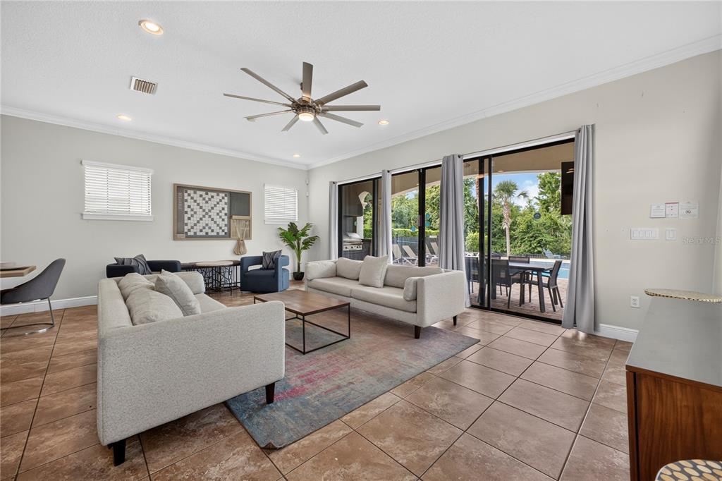 A living room features two light-colored sofas, a patterned rug, and sliding glass doors — 824 DESERT MOUNTAIN COURT, KISSIMMEE, FL