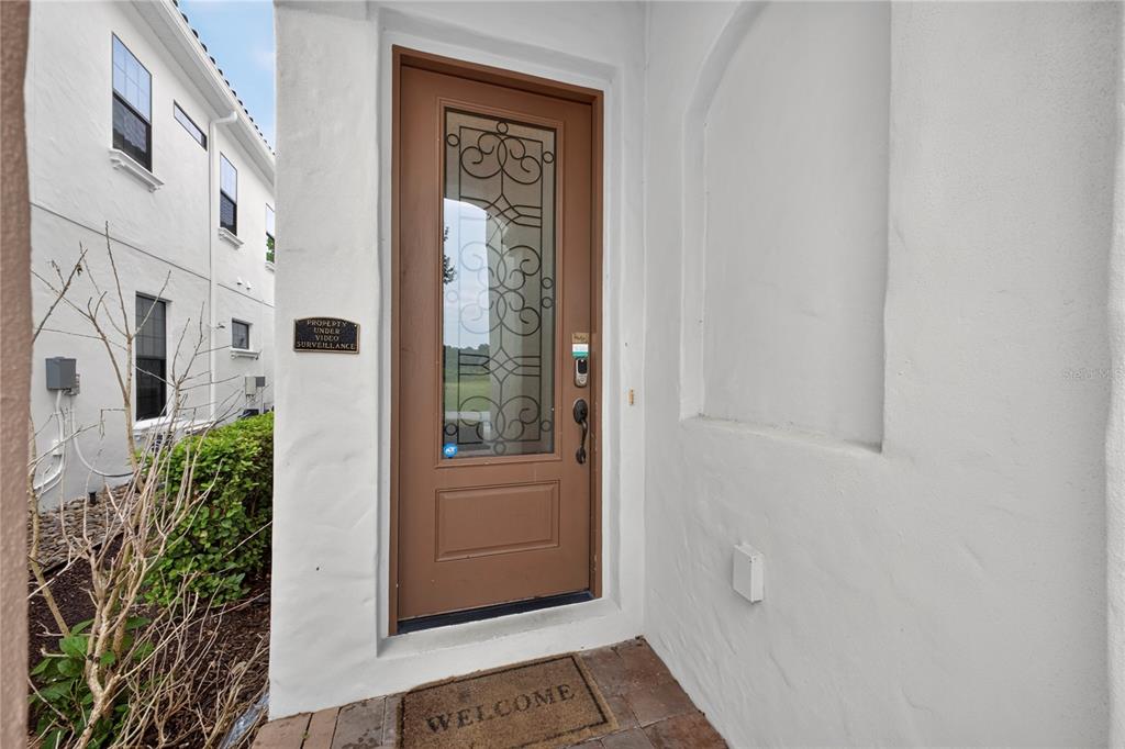 A brown front door with a decorative glass insert sits in a white stucco entryway — 824 DESERT MOUNTAIN COURT, KISSIMMEE, FL