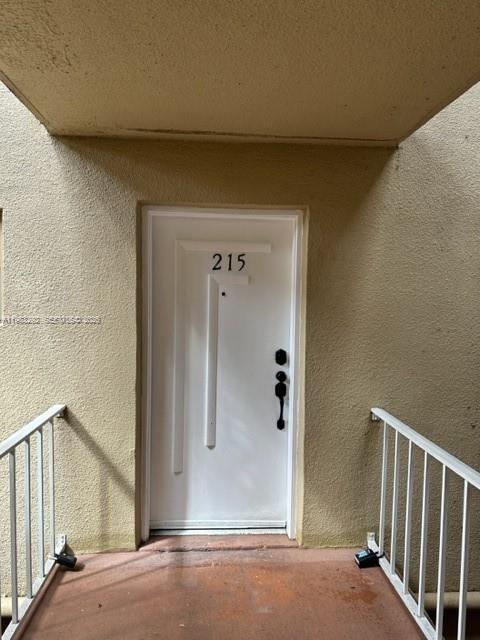 A white front door labeled 215 is situated between two white metal railings — 4255 N UNIVERSITY DR # 215, Sunrise FL 33351, SUNRISE, FL