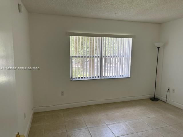 An empty room with beige tile flooring, white walls, and vertical window blinds — 4255 N UNIVERSITY DR # 215, Sunrise FL 33351, SUNRISE, FL