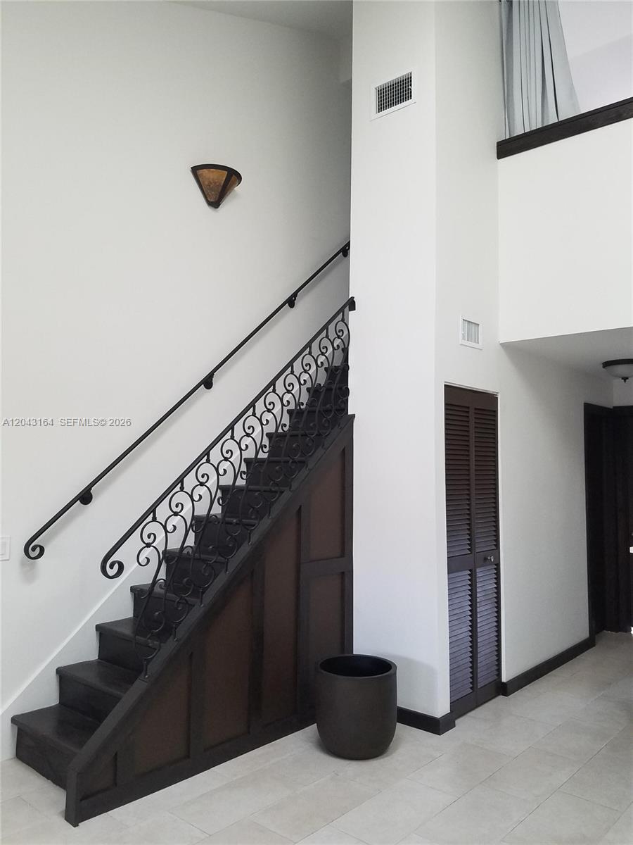 A staircase with dark wood steps and ornate iron railings sits beside a louvered door — 406 SE 14th St, Dania Beach FL 33004, DANIA BEACH, FL