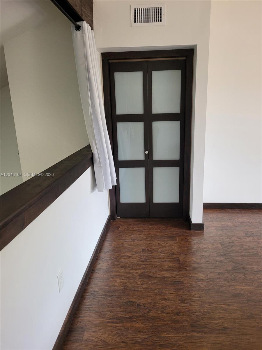 A room features dark wood-look flooring, white walls, and a set of frosted glass doors — 406 SE 14th St, Dania Beach FL 33004, DANIA BEACH, FL