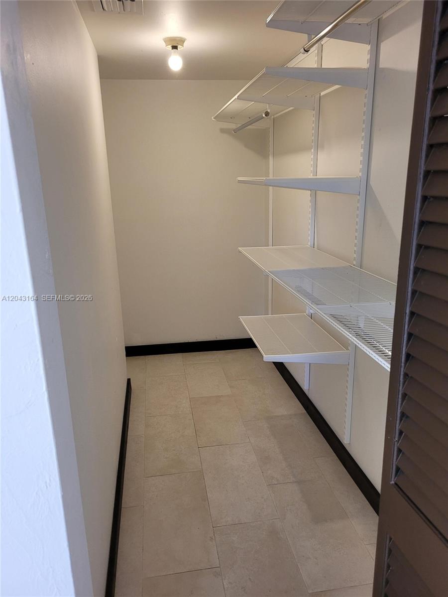 A walk-in closet features white wire shelving, light-colored tile flooring, and a single ceiling light — 406 SE 14th St, Dania Beach FL 33004, DANIA BEACH, FL