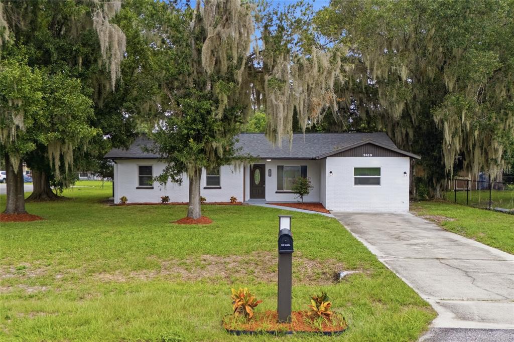 A single-story white brick house with a dark roof sits on a grassy lot — 2419 RIDGEVIEW DRIVE, LAKELAND, FL