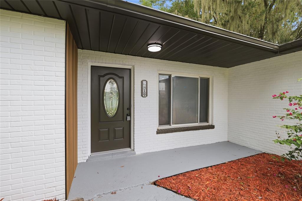 The exterior view shows a white brick house entrance with a brown door and porch — 2419 RIDGEVIEW DRIVE, LAKELAND, FL