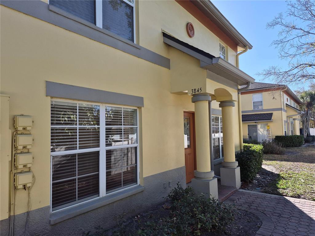 A yellow two-story building features a covered entrance with columns and a brick walkway — 3845 ISLAND WAY, ST PETERSBURG, FL