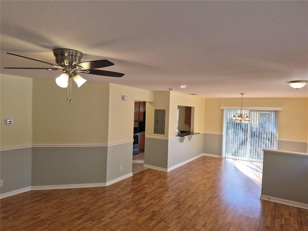An open-concept living and dining area features wood-look flooring, two-tone walls, and a ceiling fan — 3845 ISLAND WAY, ST PETERSBURG, FL