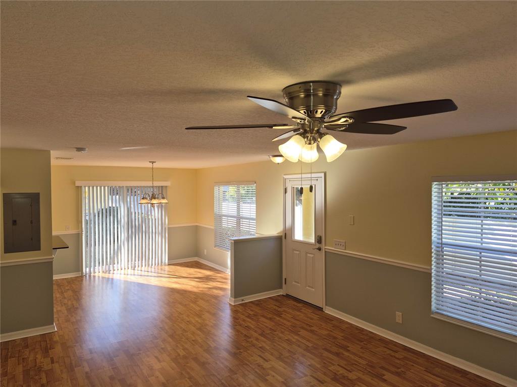A living room with wood-look flooring, a ceiling fan, and a door leading outside — 3845 ISLAND WAY, ST PETERSBURG, FL
