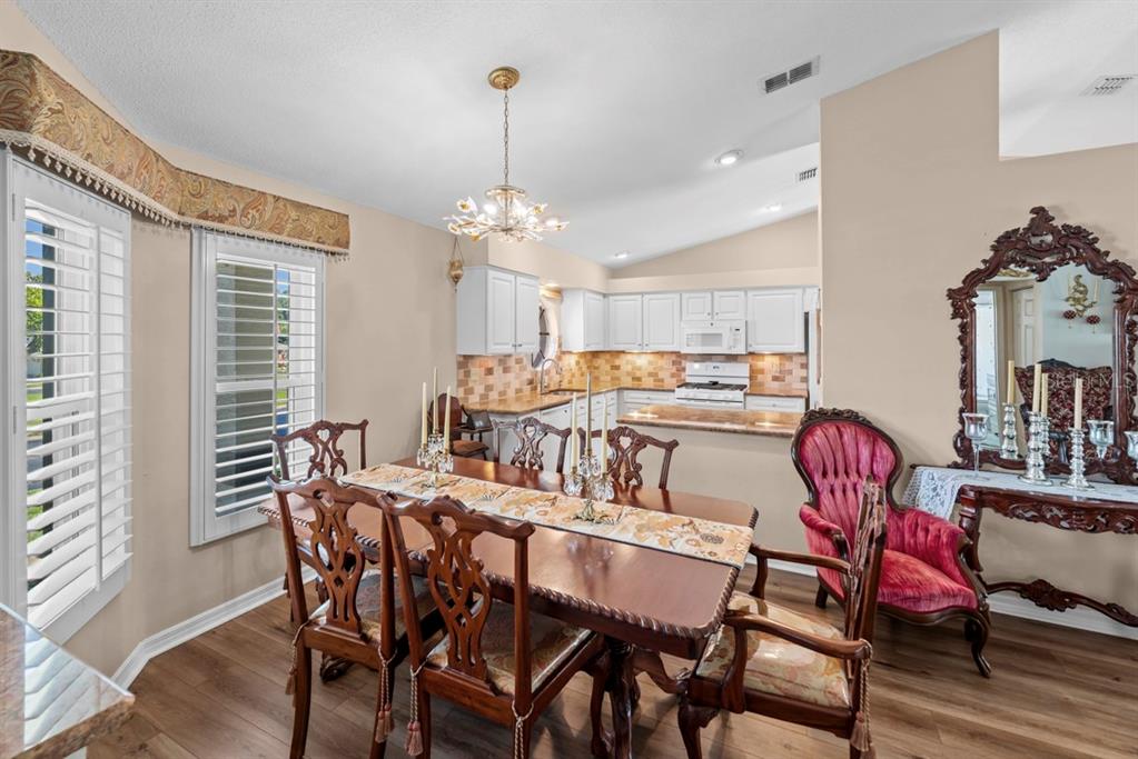 A dining room with a wooden table, ornate chairs, and an open kitchen in the background — 6323 SILVER LAKES DRIVE E, LAKELAND, FL