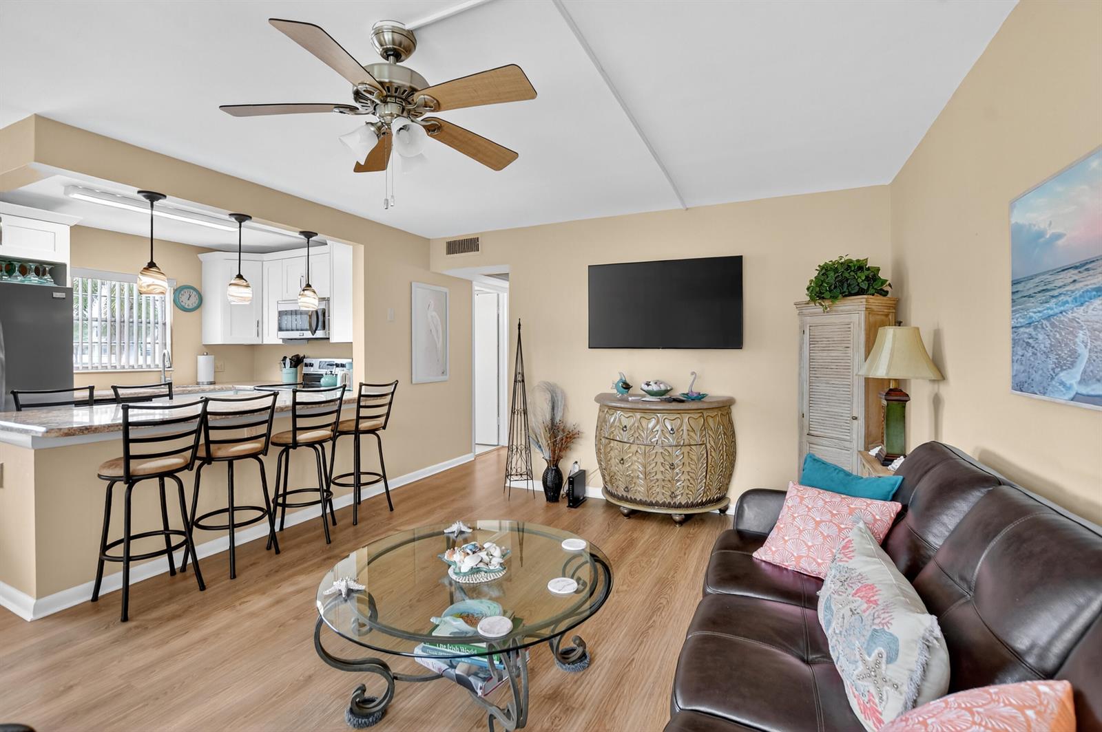A living room with a brown leather sofa, glass coffee table, and an open kitchen — 351 Fanshaw I, Boca Raton FL 33434, BOCA RATON, FL