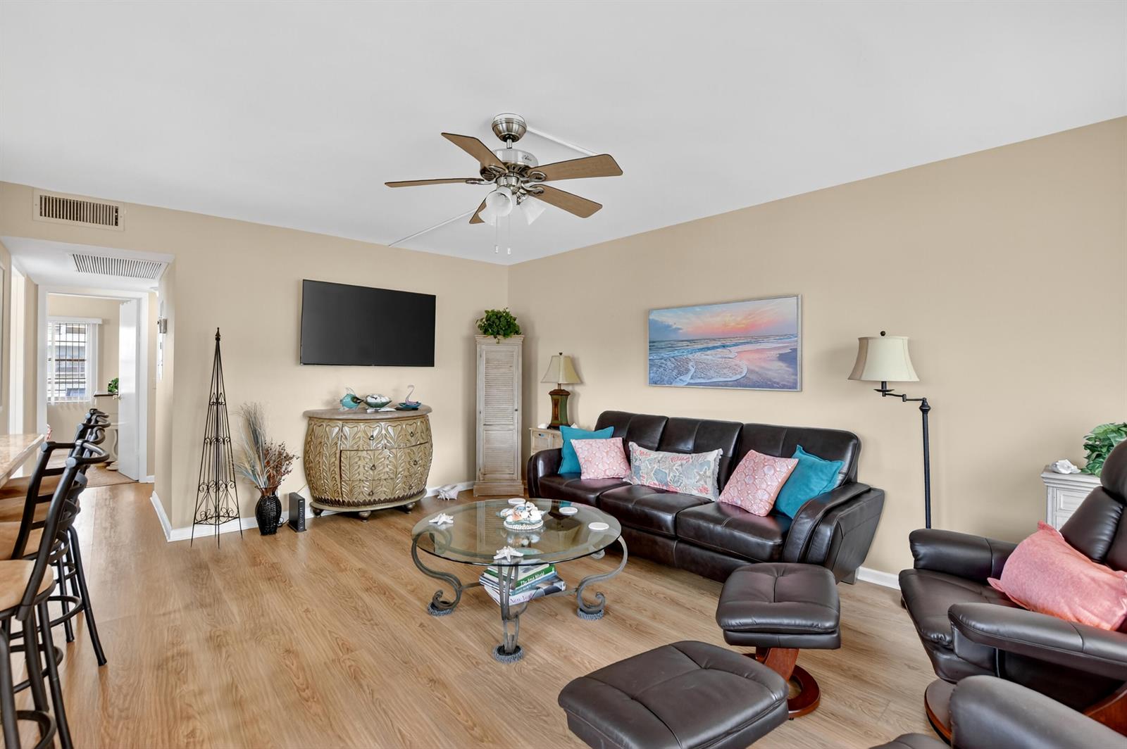 A living room features a dark leather sofa, glass coffee table, and light wood flooring — 351 Fanshaw I, Boca Raton FL 33434, BOCA RATON, FL