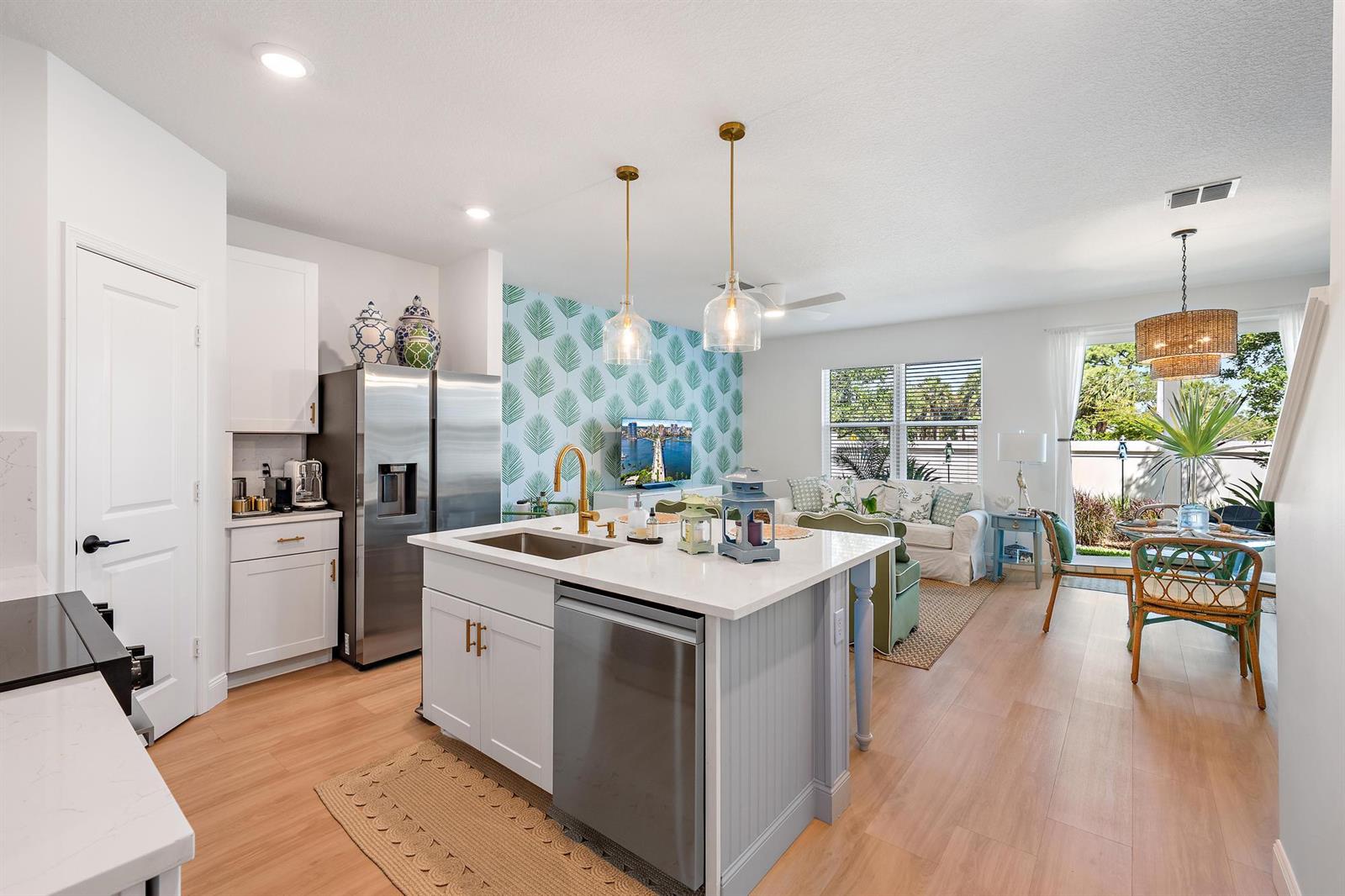 A kitchen with a central island and stainless steel appliances opens into a living area — 327 SE Halifax Lane, Stuart FL 34994, STUART, FL