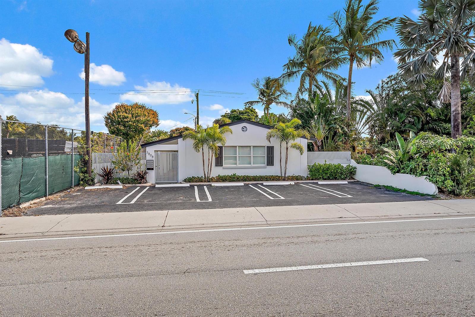 A single-story white building features a front parking lot and palm trees under blue skies — 3808 Broadway # 3, West Palm Beach FL 33407, WEST PALM BEACH, FL