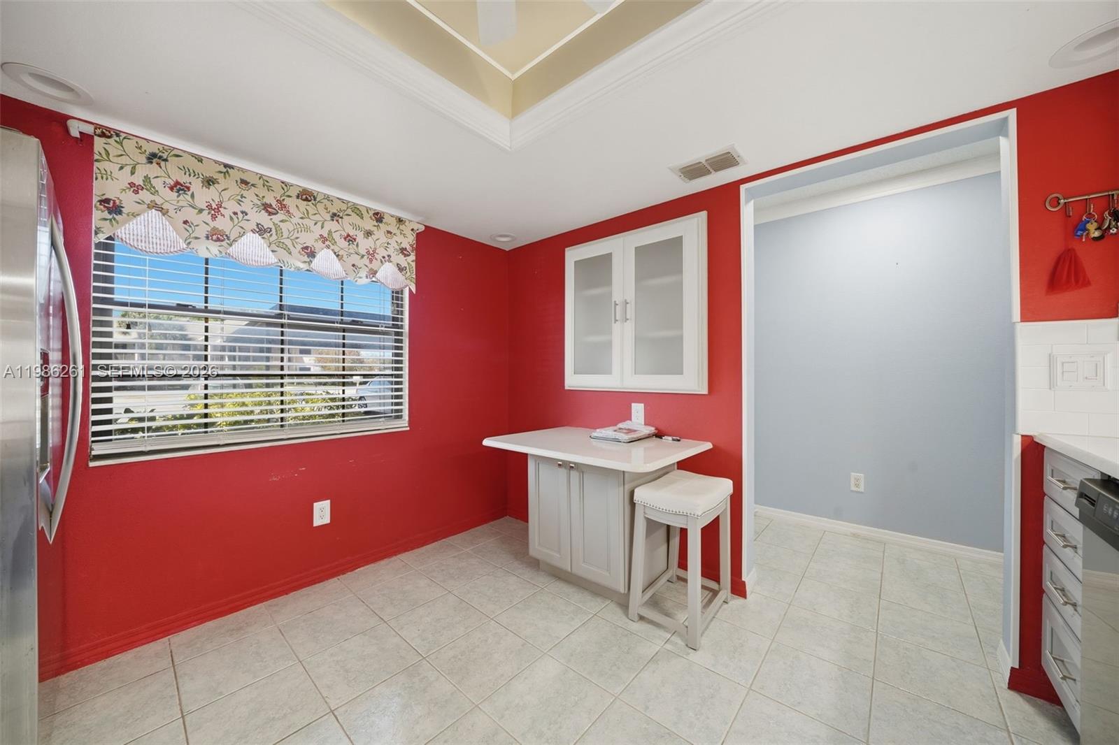 A kitchen area features red walls, light-colored tile flooring, a window with blinds, and cabinetry — 2130 ELM ST # 401, Clearwater FL 34698, CLEARWATER, FL
