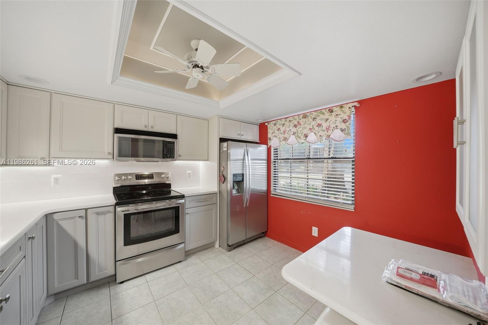 A kitchen features light gray cabinets, stainless steel appliances, white countertops, and a red wall — 2130 ELM ST # 401, Clearwater FL 34698, CLEARWATER, FL