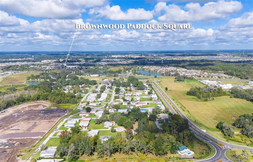 This aerial view shows a residential neighborhood with houses, trees, and a nearby road — LOT 60 BLK C LEXINGTON CIRCLE, WILDWOOD, FL