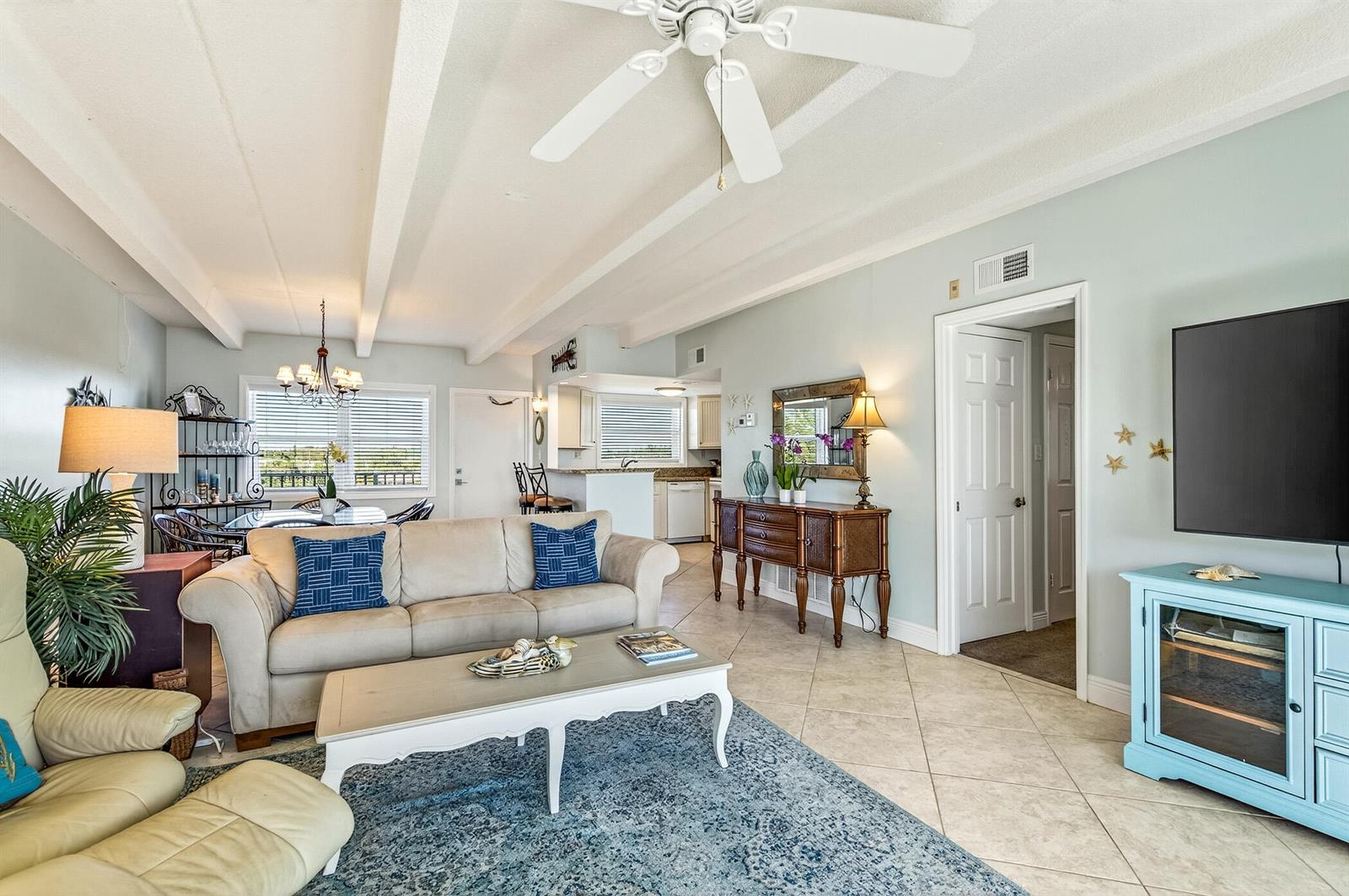 A living room with a beige sofa, blue area rug, and a light blue TV console — 4410 Highway A1a # 307, Vero Beach FL 32963, VERO BEACH, FL