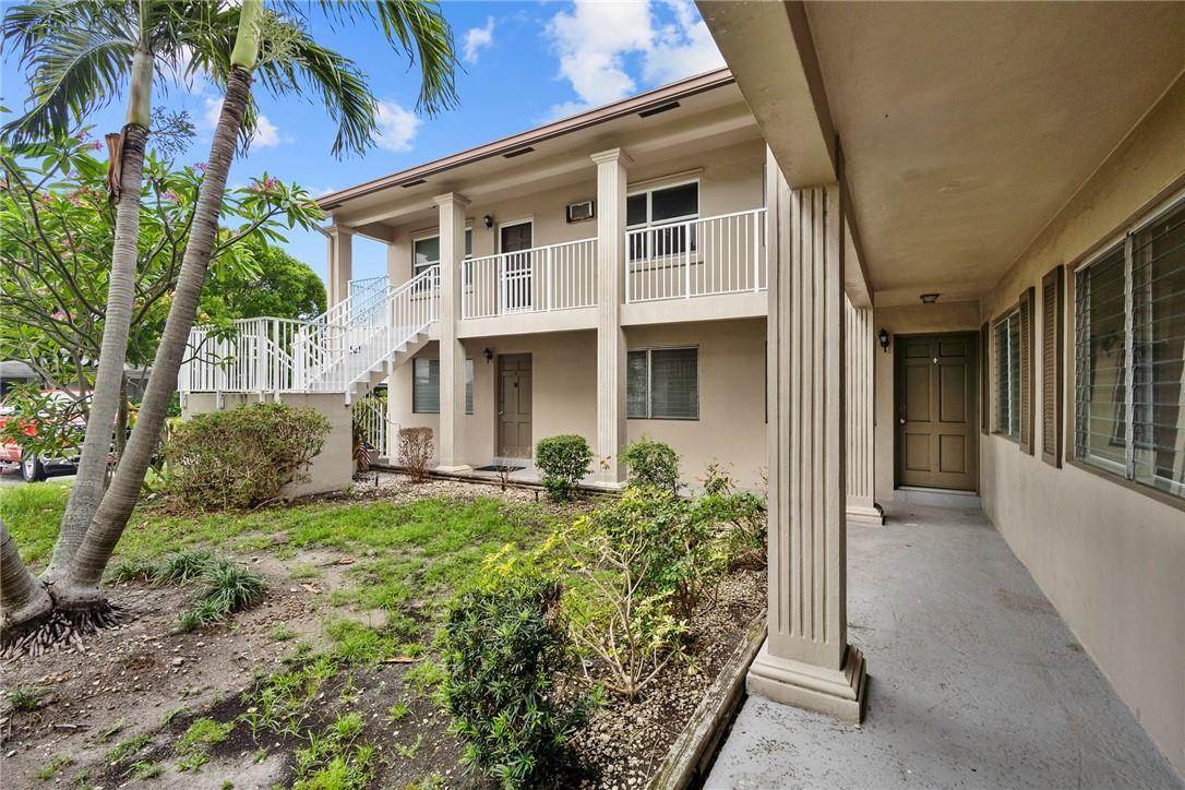 A two-story apartment building exterior features a covered walkway, white railings, and a staircase — 2130 NE 42nd Court # 4, Lighthouse Point FL 33064, LIGHTHOUSE POINT, FL