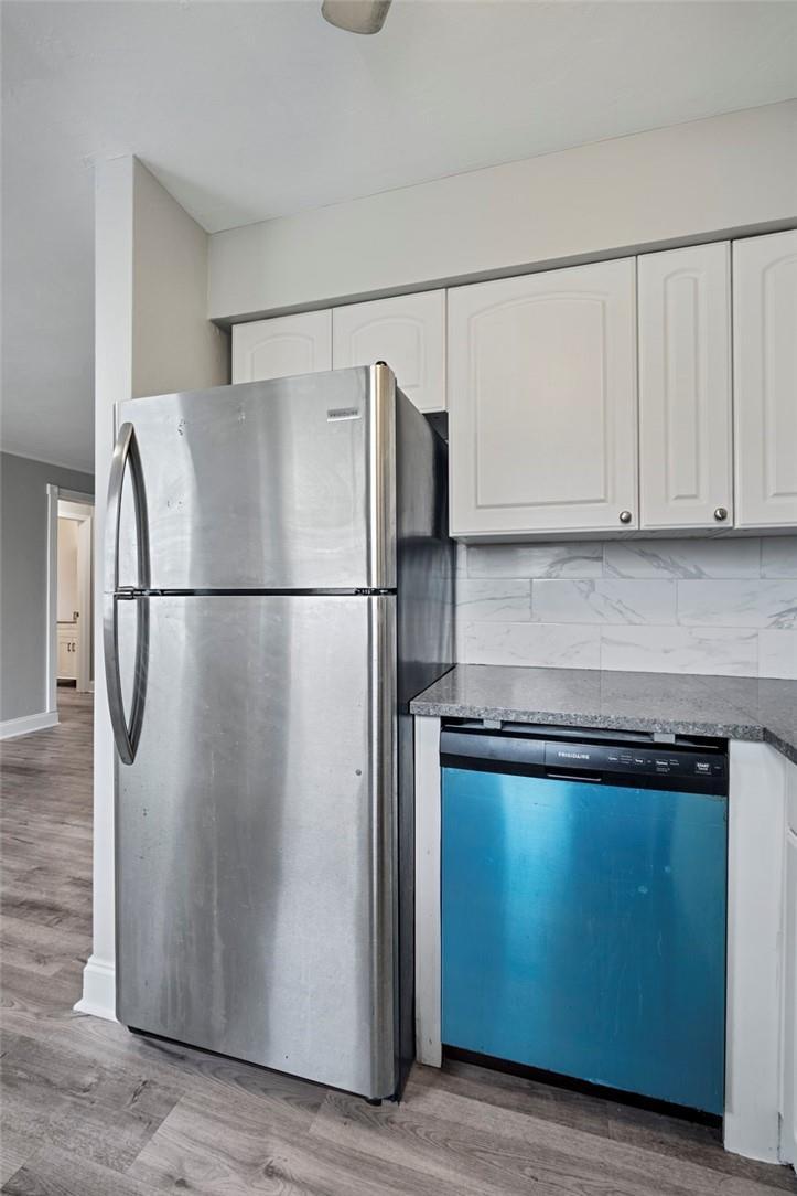 A stainless steel refrigerator stands next to a dishwasher beneath white cabinets and granite countertops — 2130 NE 42nd Court # 4, Lighthouse Point FL 33064, LIGHTHOUSE POINT, FL