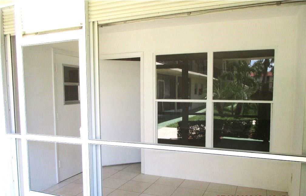 A screened-in patio features white walls, tiled flooring, and a view of outdoor landscaping — 804 SE 7th Street # 101, Deerfield Beach FL 33441, DEERFIELD BEACH, FL