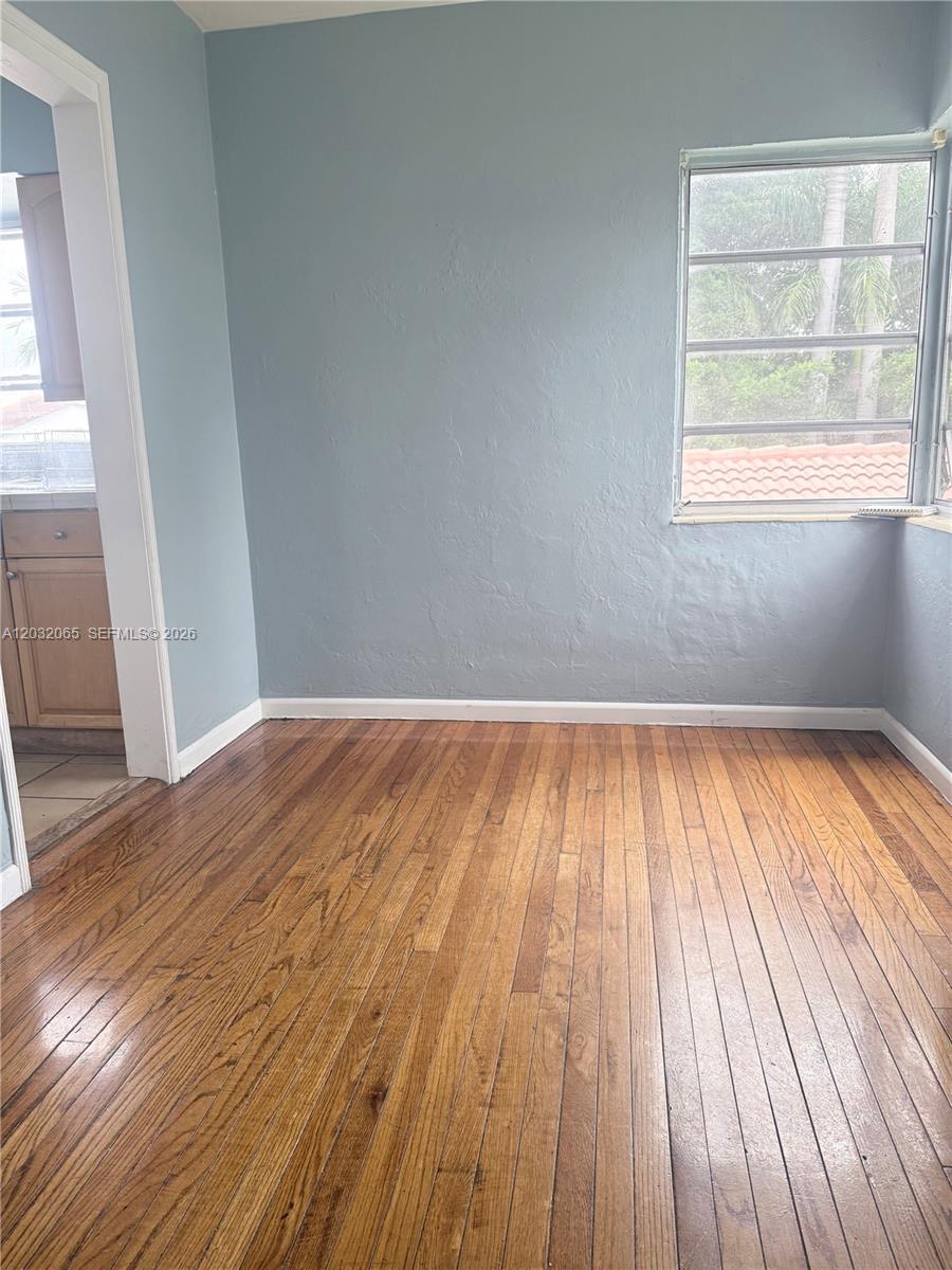 A room with hardwood floors, light blue walls, and a window overlooking a tiled roof — 1730 Marseille Dr # 4, Miami Beach FL 33141, MIAMI BEACH, FL