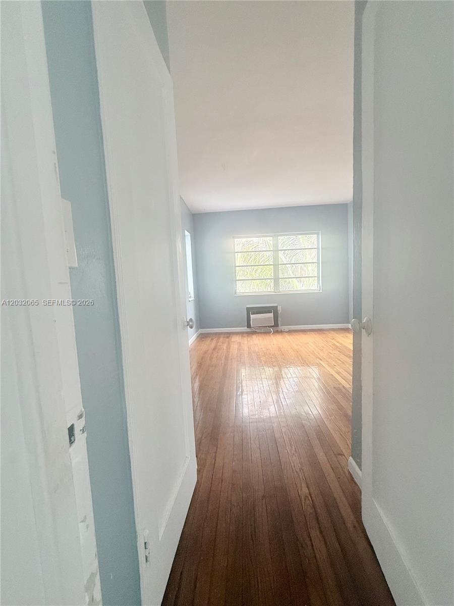 A view through a doorway shows an empty room with hardwood floors and light-blue walls — 1730 Marseille Dr # 4, Miami Beach FL 33141, MIAMI BEACH, FL