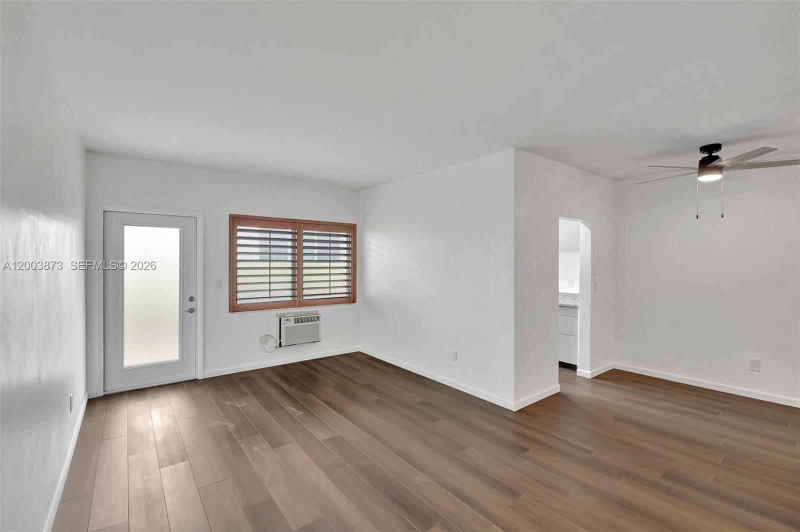 An empty room features white walls, wood-look flooring, a ceiling fan, and a window unit — 1334 Euclid Ave # 8, Miami Beach FL 33139, MIAMI BEACH, FL
