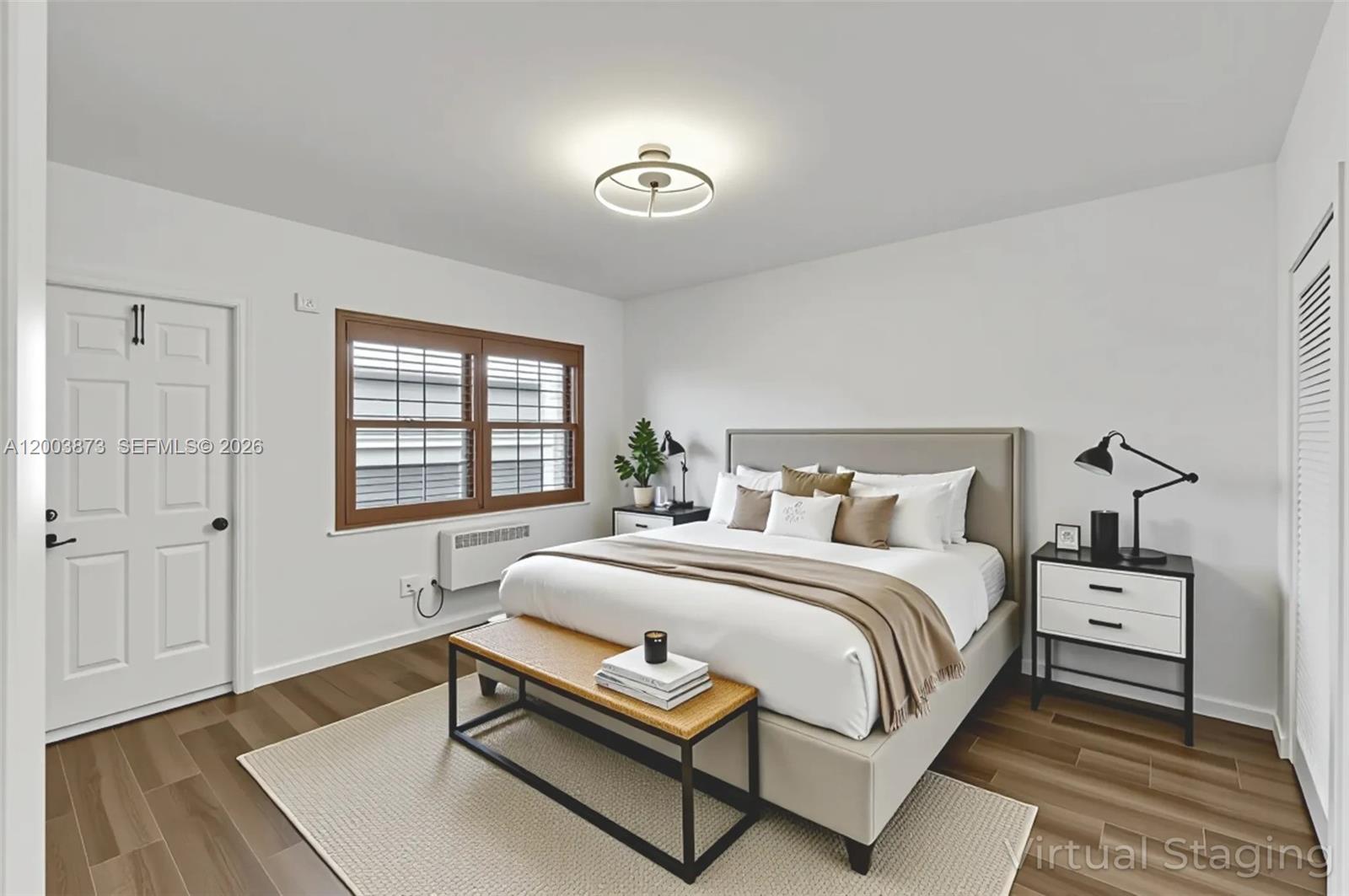 A bedroom features a bed with a neutral headboard, a wooden bench, and dark flooring — 1334 Euclid Ave # 8, Miami Beach FL 33139, MIAMI BEACH, FL