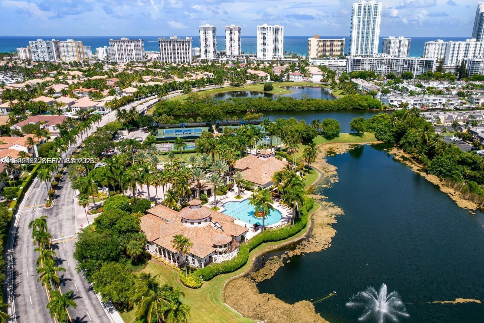 An aerial view shows a clubhouse with a pool, tennis courts, and a lake — 963 S Harbor Vw S, Hollywood FL 33019, HOLLYWOOD, FL