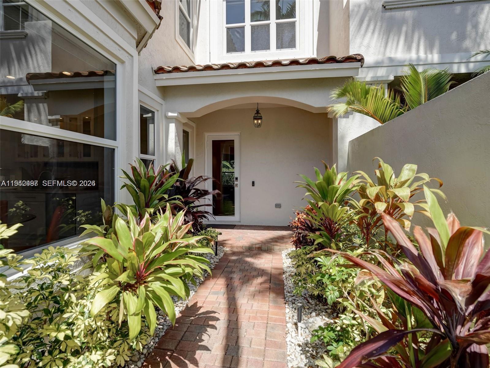 A brick walkway leads to the front entrance of a house with tropical landscaping — 963 S Harbor Vw S, Hollywood FL 33019, HOLLYWOOD, FL